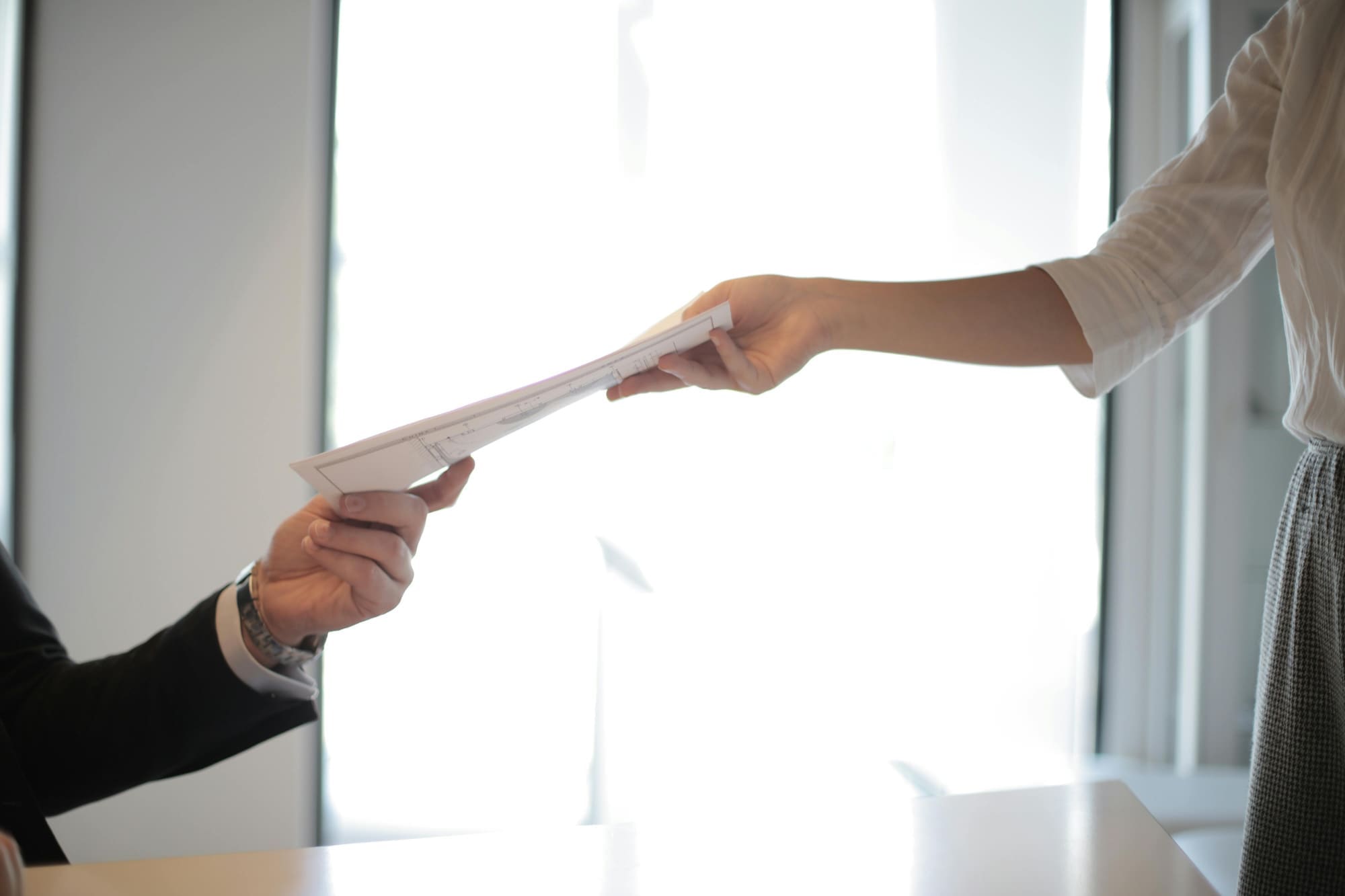 Somebody handing a paper document to somebody else.