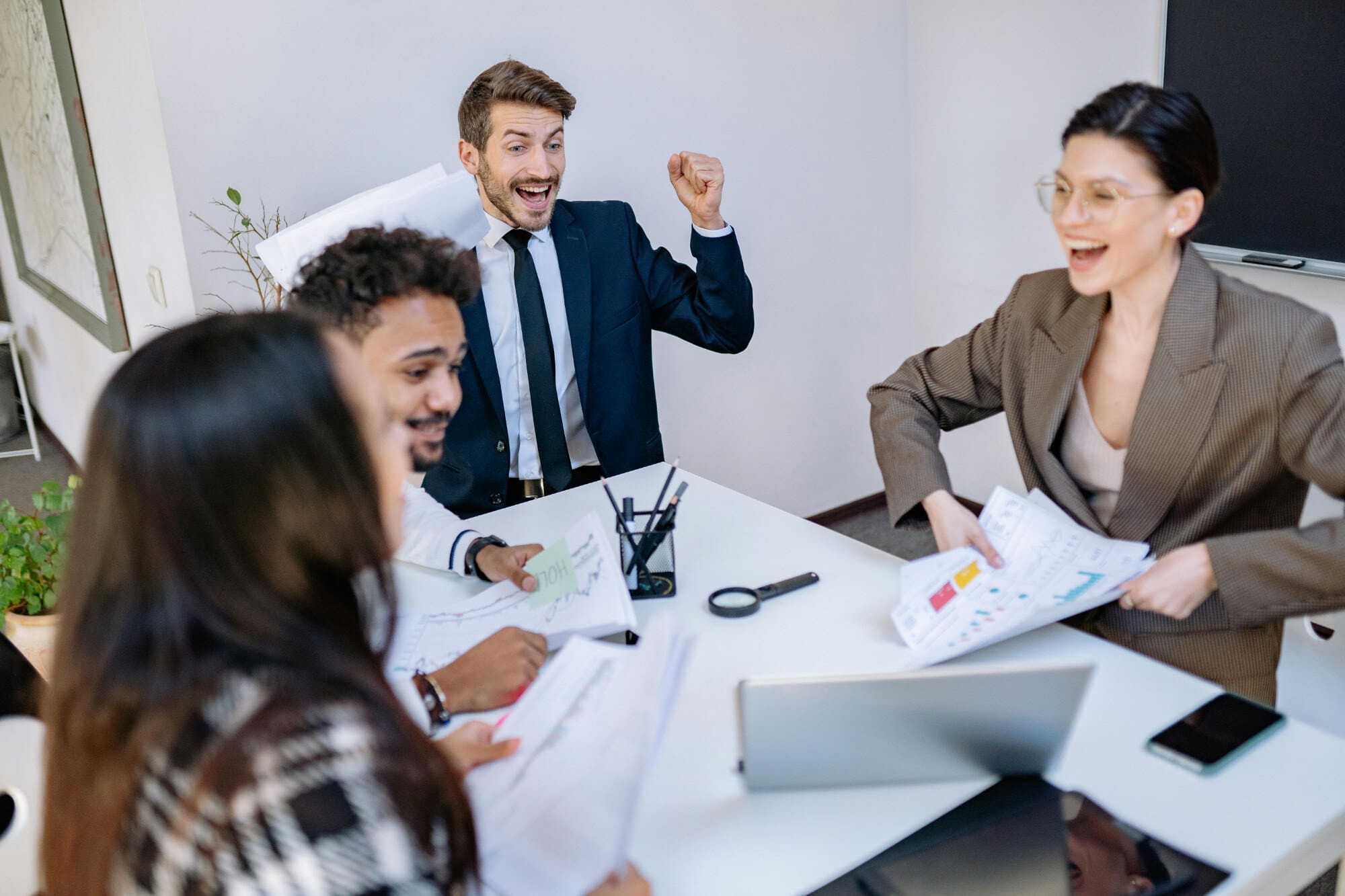 Happy smiling office workers sitting around desk and looking at business charts.