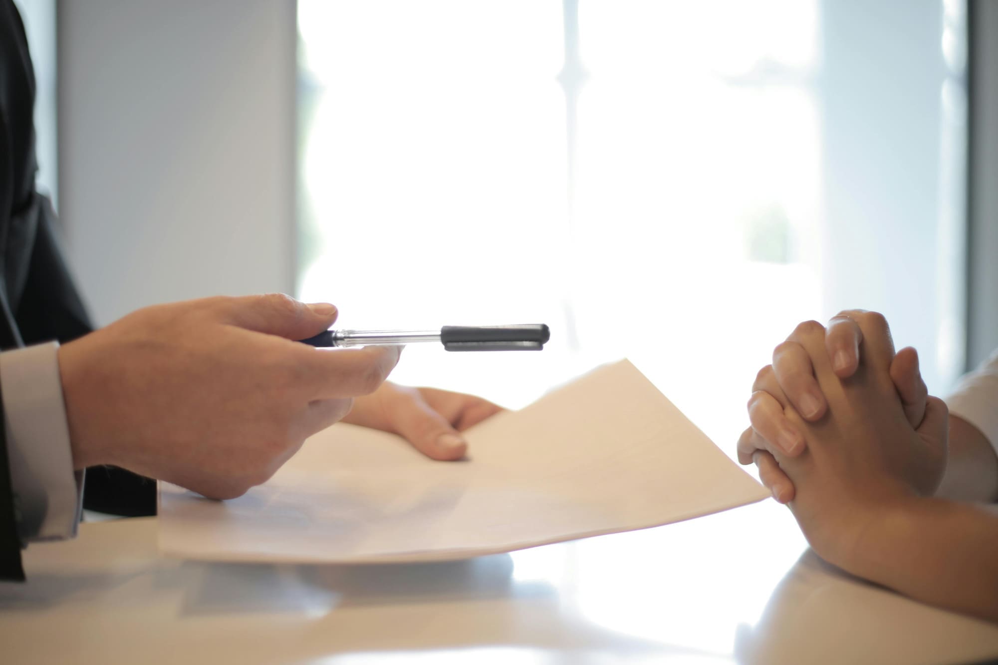 One office worker handing a pen and paper to another.