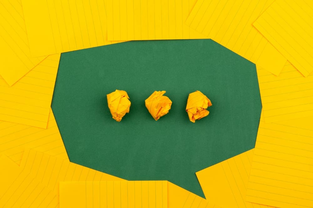 Yellow paper placed on top of green paper to make the shape of a speech bubble in green.