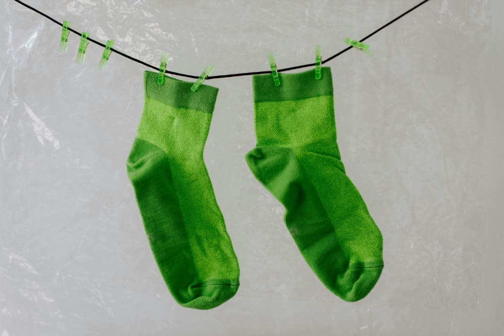 Two green-dyed socks hanging on a washing line.