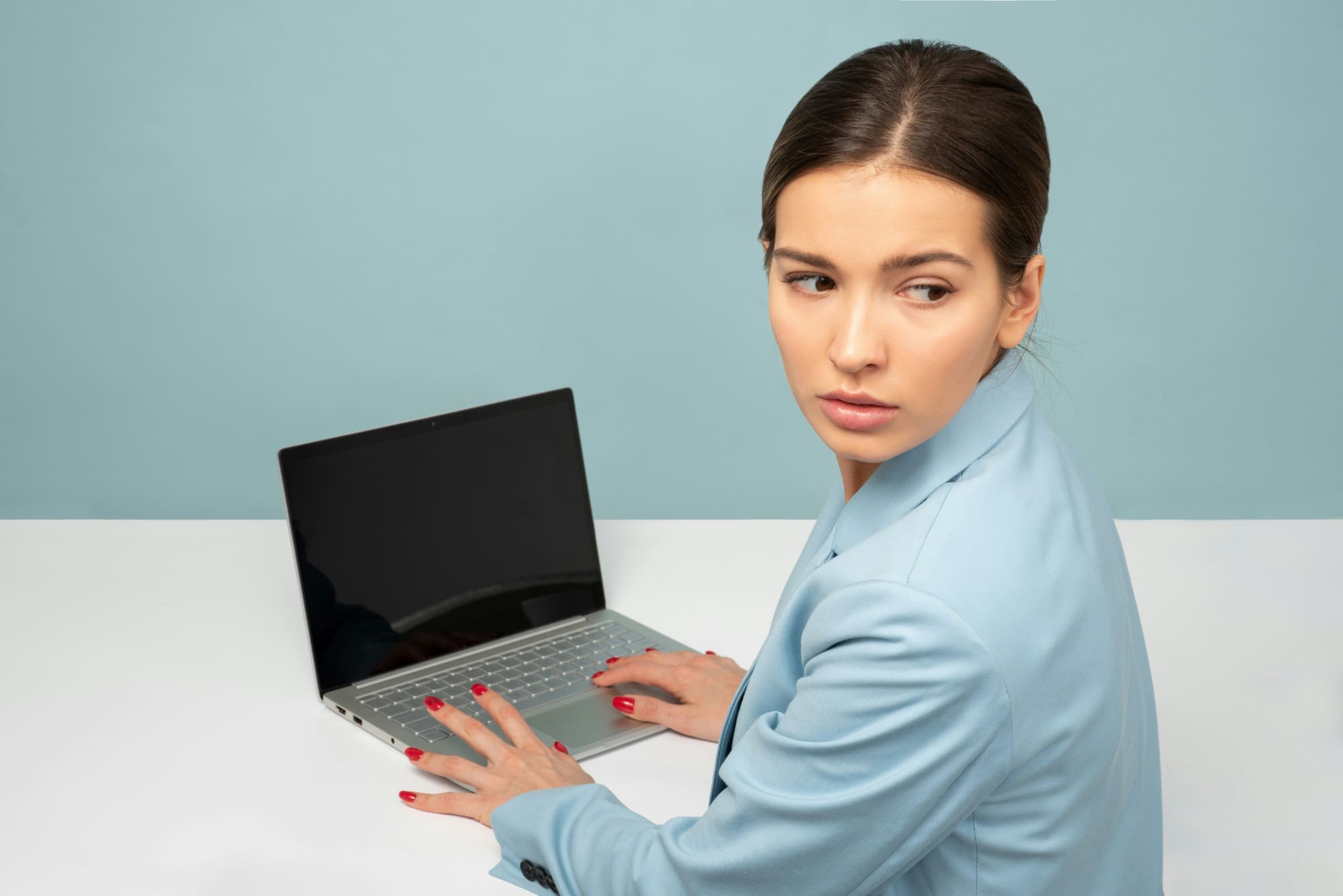 A woman sitting at desk in front of laptop but looking behind her.