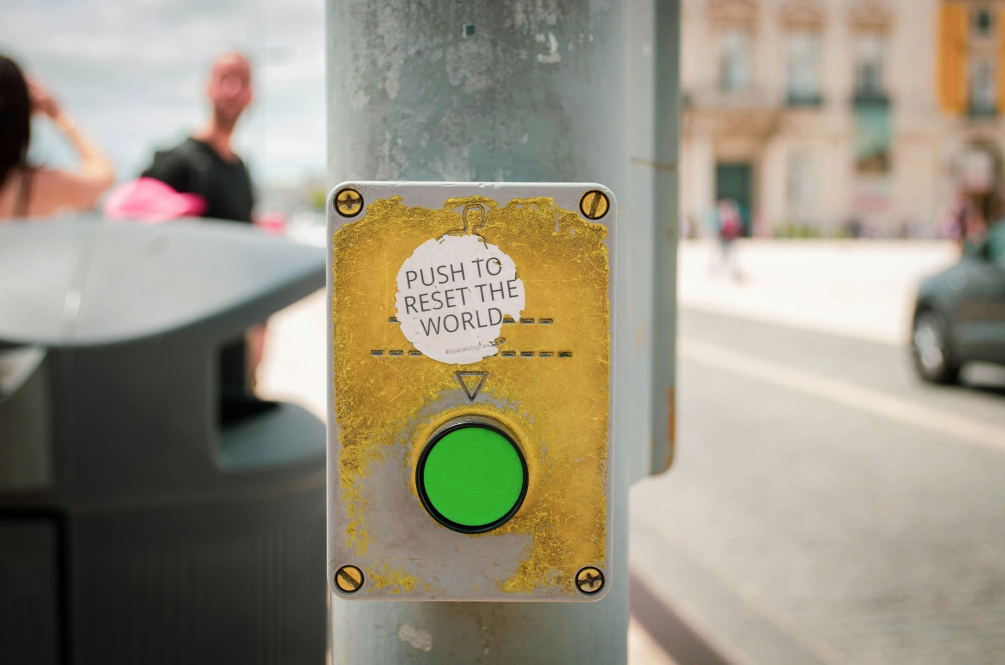 Sustainability Staff On-Demand A green button attached to a street pole with the words 'Push to reset the world' written above it.