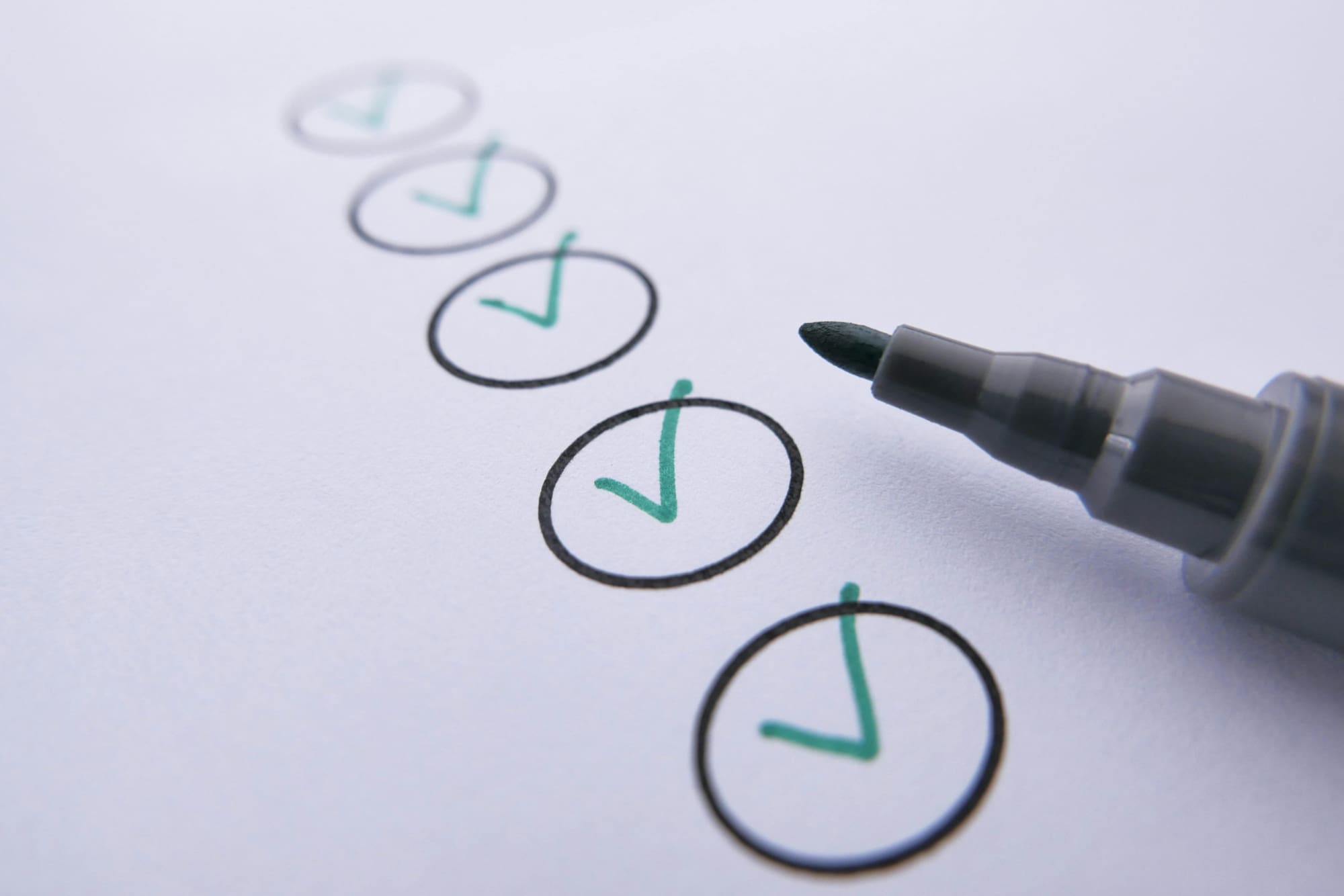 A white page with black circles ticked with a green marker.