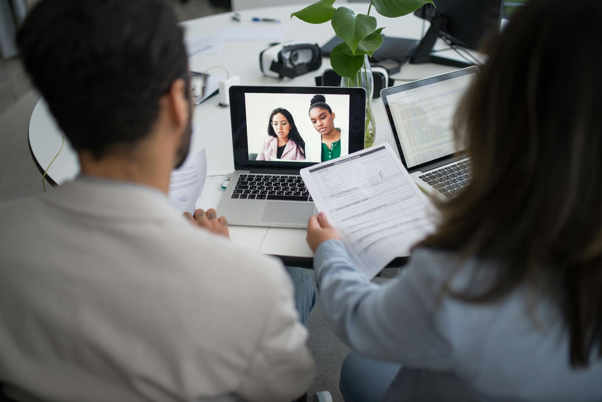 Two office workers video calling other workers on laptop.