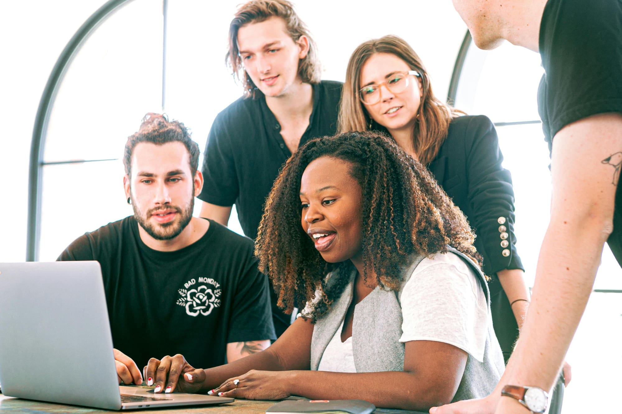 Several office workers crowded around a laptop looking at the screen.
