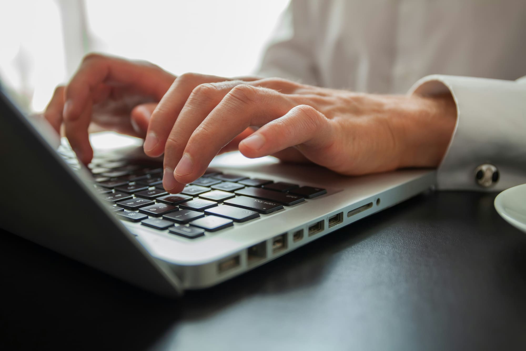 Register company profile Close-up image of somebody typing on a laptop keyboard.