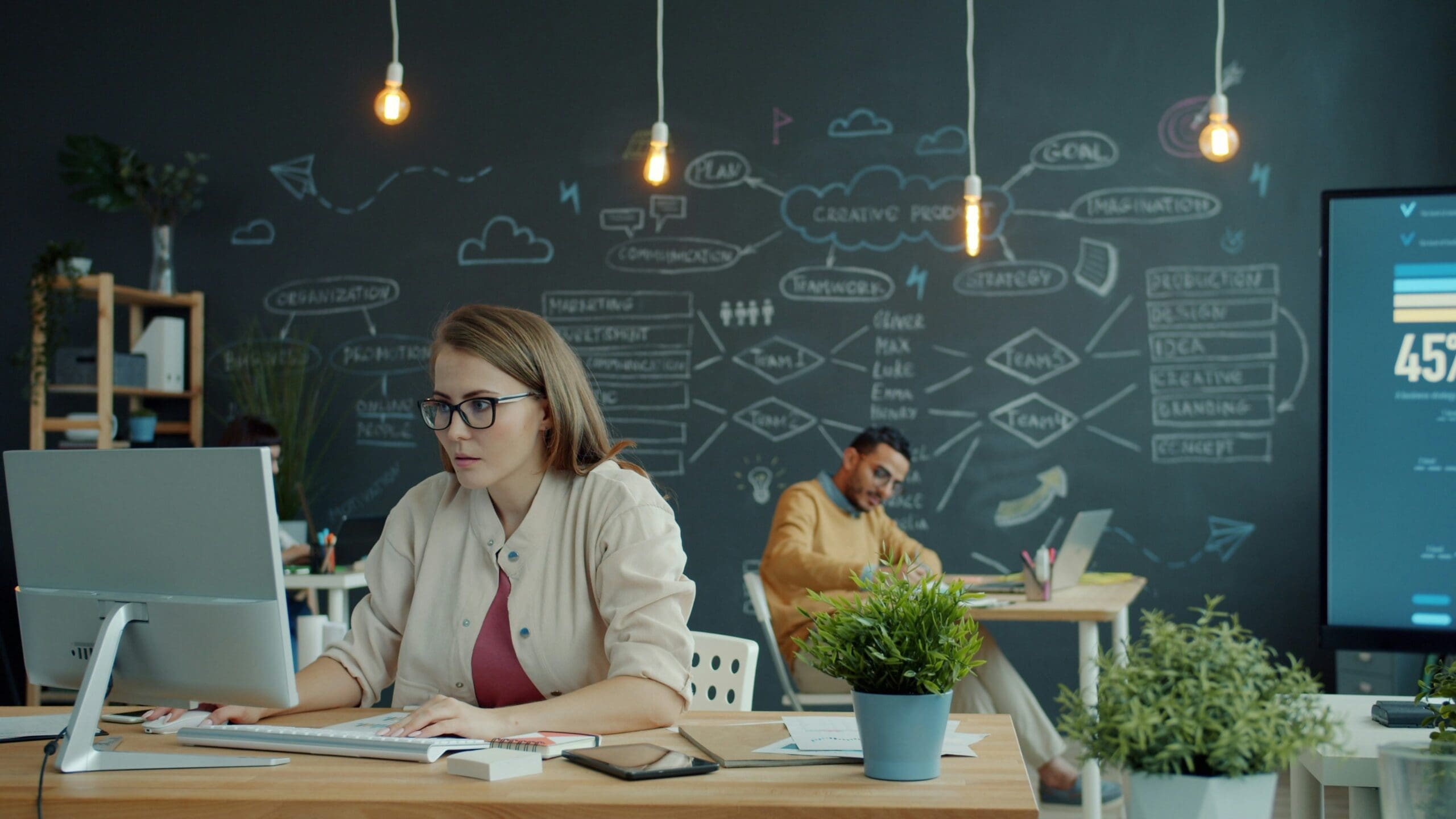 Professional working at a computer with a strategy board in the background, representing data strategy development for Scope 3 emissions